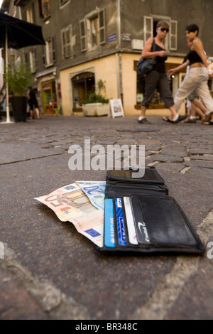 Verlorene Geldbörse mit Euro / Europäische Banknoten und zeigt UK Bank- und Kreditkarten, liegend auf einer gepflasterten Straße in Frankreich. Stockfoto