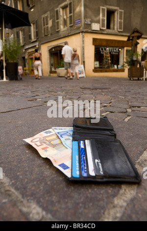 Verlorene Geldbörse mit Euro / Europäische Banknoten und zeigt UK Bank- und Kreditkarten, liegend auf einer gepflasterten Straße in Frankreich. Stockfoto