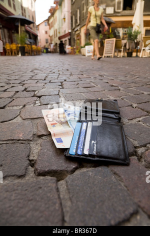 Verlorene Geldbörse mit Euro / Europäische Banknoten und zeigt UK Bank- und Kreditkarten, liegend auf einer gepflasterten Straße in Frankreich. Stockfoto