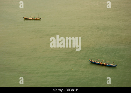 Zwei kleine traditionelle ghanaische Angelboote/Fischerboote vor Anker in Ruhe Mittag Gewässern vor der Küste von Cape Coast. Stockfoto