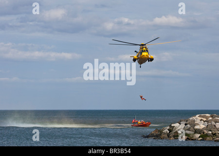 RAF-Meerkönigs Rettungshubschrauber, senkt eine Winchman an einem wartenden RNLI inshore Rettungsboot. Stockfoto