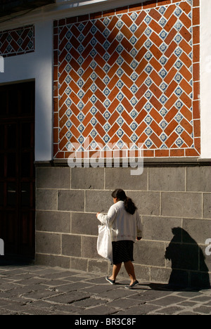 Frau zu Fuß vorbei an Talavera Fliesen auf eine Gebäude-Fassade die Stadt Puebla, Mexiko. Puebla ist ein UNESCO-Weltkulturerbe. Stockfoto