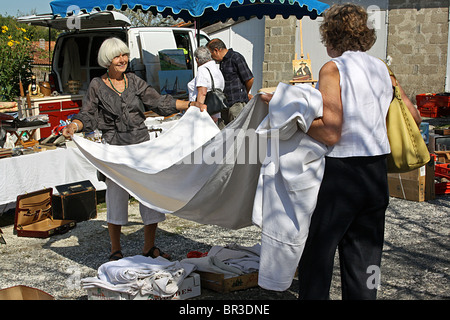 Zwei Frauen, die Prüfung Leinen zum Verkauf an Brocante, in das Dorf von St. Quentin-de-Chalais, Frankreich. Stockfoto