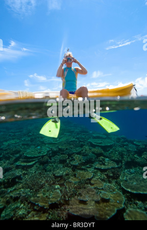 Split-Level-Wasser erschossen Blick auf eine Frau sitzt auf einem Sit-on-Top Kajak mit ihren Füßen in das blaue Wasser unten hängen. Fidschi-Inseln. Stockfoto