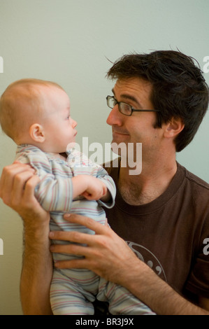 Reifer Mann macht lustige Gesicht Baby Baby In Händen halten Stockfoto