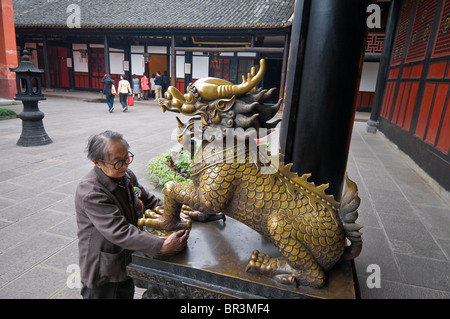 Älteren Verehrer streichelt Messing Löwe zur Verbesserung der Gesundheit, Wenshu Tempel, Chengdu, Provinz Sichuan, China Stockfoto