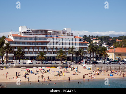 Sonnenanbeter am Strand von Cascais, ein Ferienort in der Nähe von Lissabon, Portugal. Das 3-Sterne Hotel Baia mit Blick auf die Bucht. Stockfoto