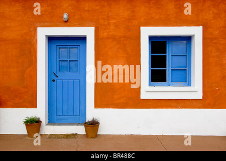 Schöne und lustige orange Haus mit blauen Türen und Fenstern Stockfoto