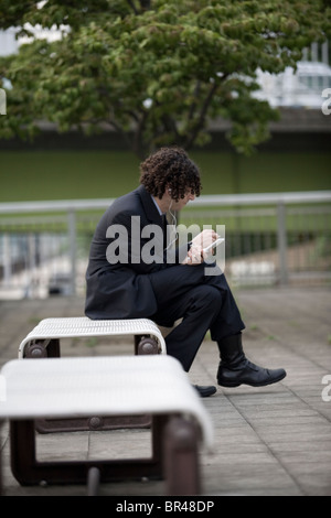 Geschäftsmann im Anzug arbeiten am Handgerät auf Bank Tokio, Japan. Stockfoto