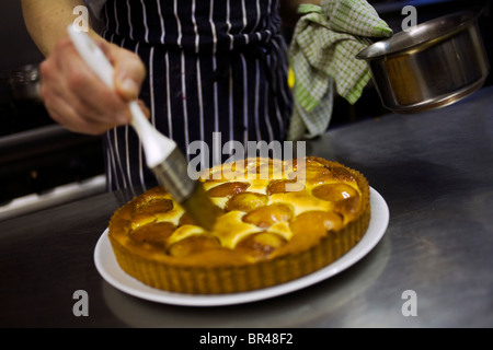Ein Koch Verglasung eine Aprikosen-Tarte. Stockfoto