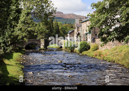 Beddgelert, Gwynedd, North Wales, UK, Europa. Blick entlang Afon Colwyn Fluss, die alte Bogenbrücke im Dorfzentrum Stockfoto