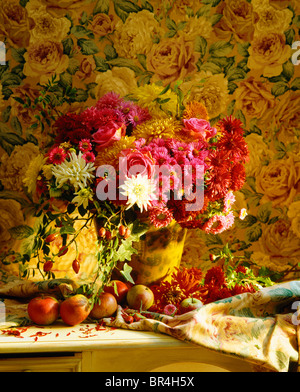 Still-Leben im Sommer Vase des späten rosa Rosen und roten Astern in gelben Vasen gegen Rose-gemusterten Tapete Stockfoto