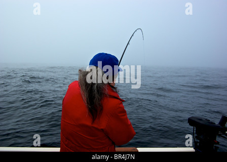 Frau Sport Angler spielen Lachs offshore im nebligen offenen Pazifik in der Nähe von Ucluelet Stockfoto