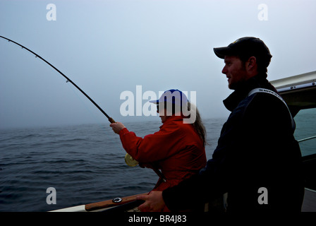 Reiseführer, die darauf warten, net Lachs Frau Angler spielen Königslachs offshore im nebligen offenen Pazifik in der Nähe von Ucluelet Stockfoto