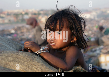 Ein junges Mädchen, das ein Kind Arbeiter, starrt auf die untergehende Sonne bei Stung Meanchey Mülldeponie in Phnom Penh, Kambodscha. Stockfoto