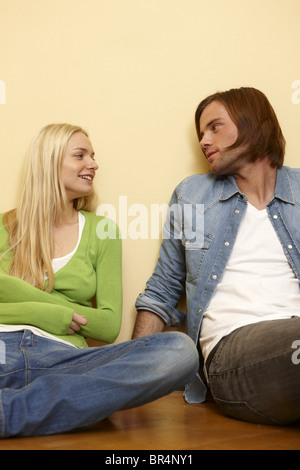 Junges Paar sitzt am Boden lächelnd Stockfoto