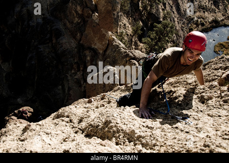 Ein Bergsteiger lächelt, als er oben auf einer Route nähert. Stockfoto