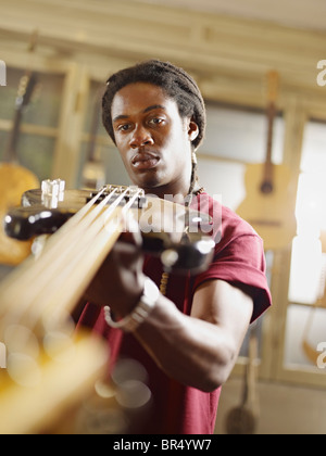 Afrikanische amerikanische Handwerker betrachten Gitarre in Werkstatt Stockfoto