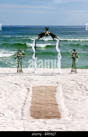 Torbogen mit Blumen und Teppich sind für eine Hochzeit am Strand errichtet. Stockfoto