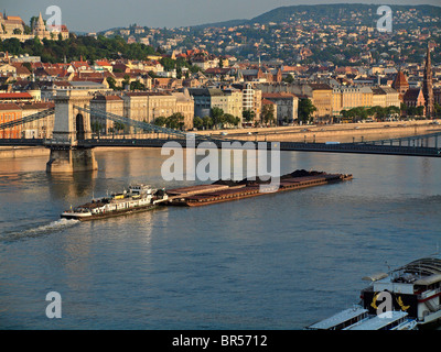 Ein Kohle-Lastkahn unterquert die Kettenbrücke über die Donau bei Sonnenaufgang. Budapest, Ungarn Stockfoto