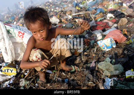 Ein junges Kind Arbeiter greift die Gaffel, die er benutzt, um Kunststoff bei Stung Meanchey Mülldeponie in Phnom Penh, Kambodscha zu sammeln. Stockfoto