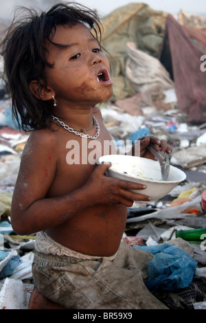 Ein hungriges Kind junge Arbeitnehmer erfüllt ihren Hunger durch den Verzehr einer Mahls bei Stung Meanchey Mülldeponie in Phnom Penh, Kambodscha. Stockfoto