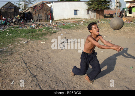 Ein junger Mann, der eine Schnitzeljagd auf der Stung Meanchey Deponie in Phnom Penh, Kambodscha ist, genießt eine Partie Beachvolleyball. Stockfoto