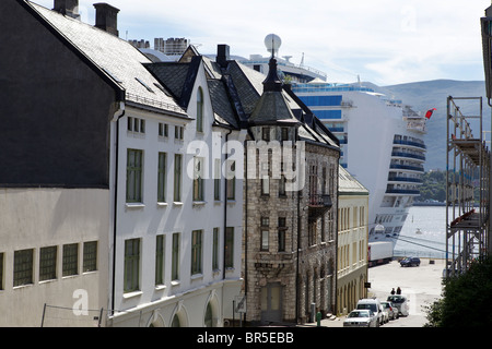 Eine Reihe von Häusern in einer Fjord-Seitenstraße in Aalesund Norwegen mit dem Kreuzfahrtschiff Kronprinzessin am Ende der Zeile sichtbar Stockfoto