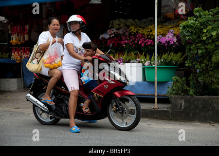 Zwei Thai-Frauen und ein kleines Kind reiten einen Roller, Phuket, Thailand Stockfoto