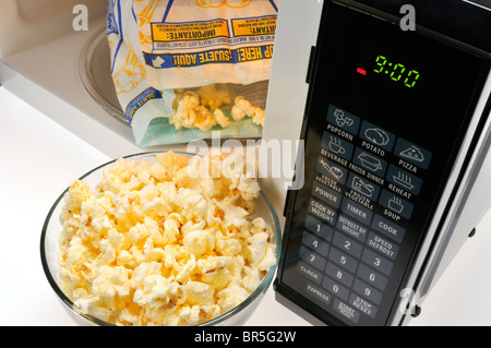 Offene Beutel mit Pop Secret mit einer Glasschale gekochten Popcorn und Mikrowelle. Stockfoto