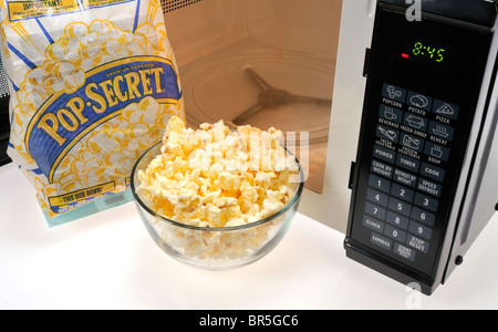 Offene Beutel mit Pop Secret mit einer Glasschale gekochten Popcorn und vor Mikrowelle. Studio. Stockfoto