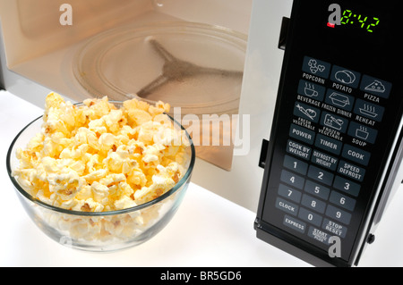 Glasschüssel von gekochten Mikrowellen-Popcorn vor Mikrowelle. Stockfoto