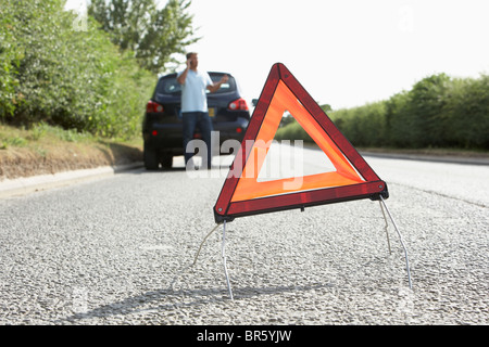 Fahrer, die Broken Down auf Landstraße mit Gefahr Warnzeichen im Vordergrund Stockfoto