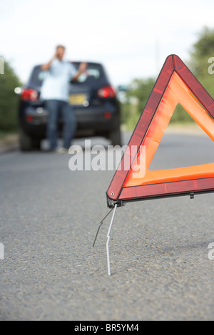 Fahrer, die Broken Down auf Landstraße mit Gefahr Warnzeichen im Vordergrund Stockfoto