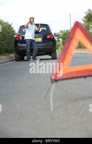 Fahrer, die Broken Down auf Landstraße mit Gefahr Warnzeichen im Vordergrund Stockfoto