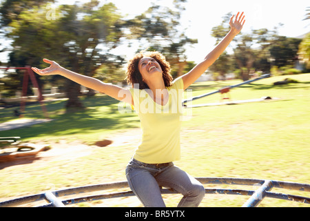 Junge Frau Reiten am Kreisverkehr im Park Stockfoto