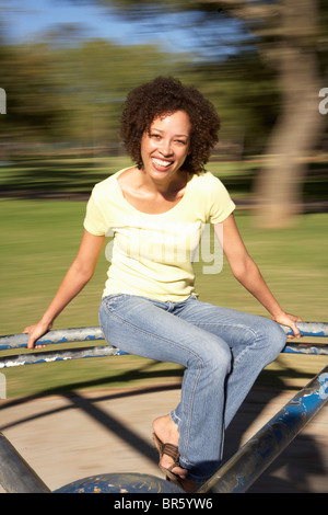 Junge Frau Reiten am Kreisverkehr im Park Stockfoto