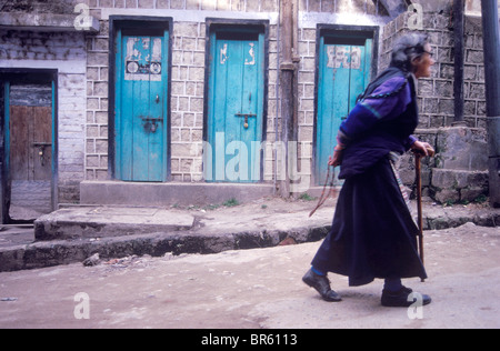 Eine ältere tibetische Frau geht die Straßen von McLeod Ganj halten Sie ihre Gebetskette hinter ihrem Rücken. Dharamsala Kangra Vall Stockfoto