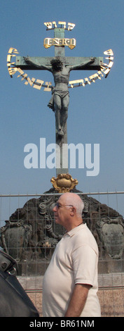 Kruzifix auf Karlsbrücke, Prag, dicker Mann vorbei. Stockfoto