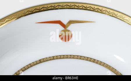 18 Porzellanstücke aus dem Dienst an Bord der Dornier DO X 1929., weißes, glasiertes Porzellan mit Zierlinien sowie ein stilisierter, geflügelter Globus in Gold und Rot. Auf der untersten Herstellermarke in unterglasuriertem Grün 'Gräf & Krippner Selb Bayern' sowie meist goldener, sporadisch schwarzer Silhouette des Wasserflugzeugs über 'DO X 1929' und 'Decoration durch Marcel Dornier Langenargen'. Bestehend aus: Suppenterrine mit zwei Griffen und Deckel, Höhe 10 cm, Durchmesser 22 cm. Sauce Boot, Höhe 10 cm, 23 x 15 cm. Milchkannikin, Höhe 13 cm. Zwei kleine, ovale Schalen, Stockfoto
