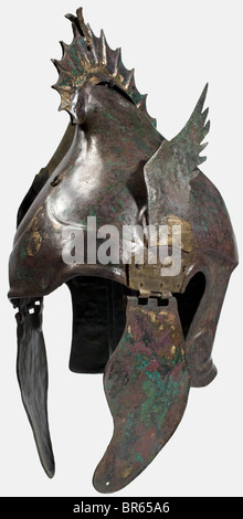 Ein Chalcidian-Helm, der sogenannte "geflügelte griffin-scheitelhelm", 4. Jahrhundert vor Christus Bronze, hoher Schädel. Das abnehmbare griffin-wappen aus zwei genieteten Blechen ist an verlöteten Haken befestigt. Glattes, eingeprägtes Feld auf der Stirn mit Lötspuren aus einer früher vorhandenen Applikation, darüber ein Befestigungsring. Voluten an den Seiten mit genieteten naturalisttisch geformten Blechflügeln. Drei zusätzliche Löcher über den Voluten sind entweder das Ergebnis einer alten Reparatur oder der Verschiebung der Flügel. Lang gebogene Wangenstücke mit Kinngurt-Löchern und röhrenförmigen Scharnieren. Stockfoto