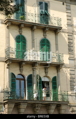 Balkone mit Fensterläden Türen und Frau kehren Stockfoto