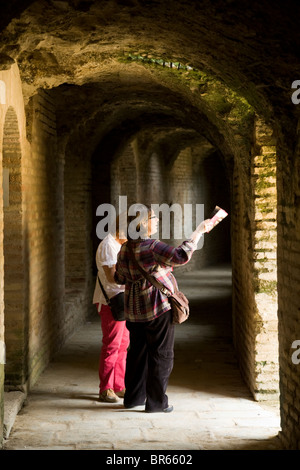 Zwei Frauen Touristen im Flur, der das Amphitheater an der zerstörten römischen Stadt Italica Kreise / Italica in der Nähe von Sevilla, Spanien. Stockfoto