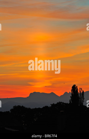 Eine Sonne-Säule, zusammen mit einer falschen Sonne im Morgengrauen auf die Schweizer Alpen Stockfoto