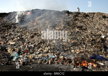 Ein Mann geht auf einem großen Hügel von verbranntem Müll bei Stung Meanchey Mülldeponie in Phnom Penh, Kambodscha. Stockfoto