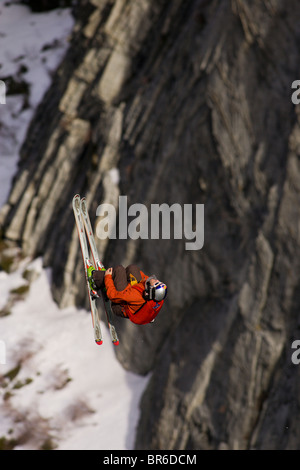 Ein männliche Ski BASE-Jumper springt ein 800 Fuß Granitklippe im Winter. Stockfoto