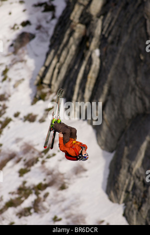 Ein männliche Ski BASE-Jumper springt ein 800 Fuß Granitklippe im Winter. Stockfoto