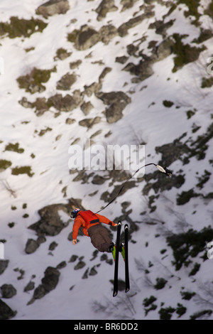 Ein männliche Ski BASE-Jumper springt ein 800 Fuß Granitklippe im Winter. Stockfoto