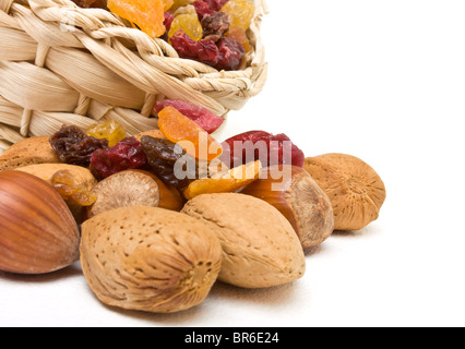 Gemischten Trockenfrüchten und Nüssen aus Korb auf weißem Hintergrund verschütten. Stockfoto