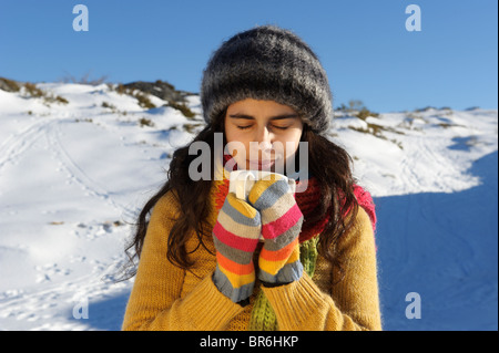 Porträt einer jungen Frau hält eine Tasse heiße Schokolade im Schnee Stockfoto